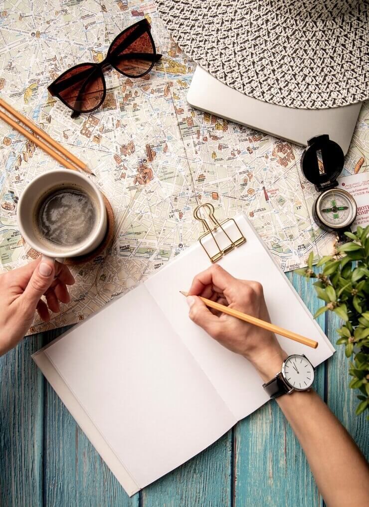 Una persona está escribiendo en un cuaderno mientras sostiene una taza de café.