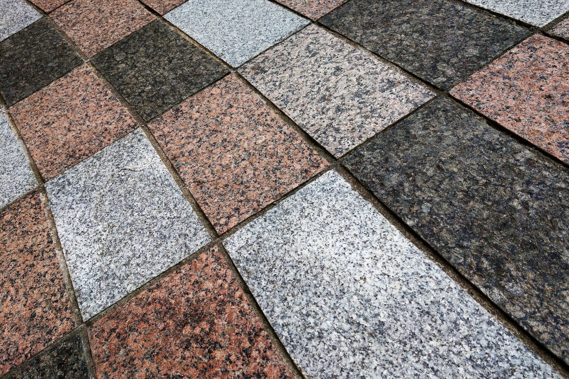 Checkered pattern of granite paving stones in gray, pink, and black.