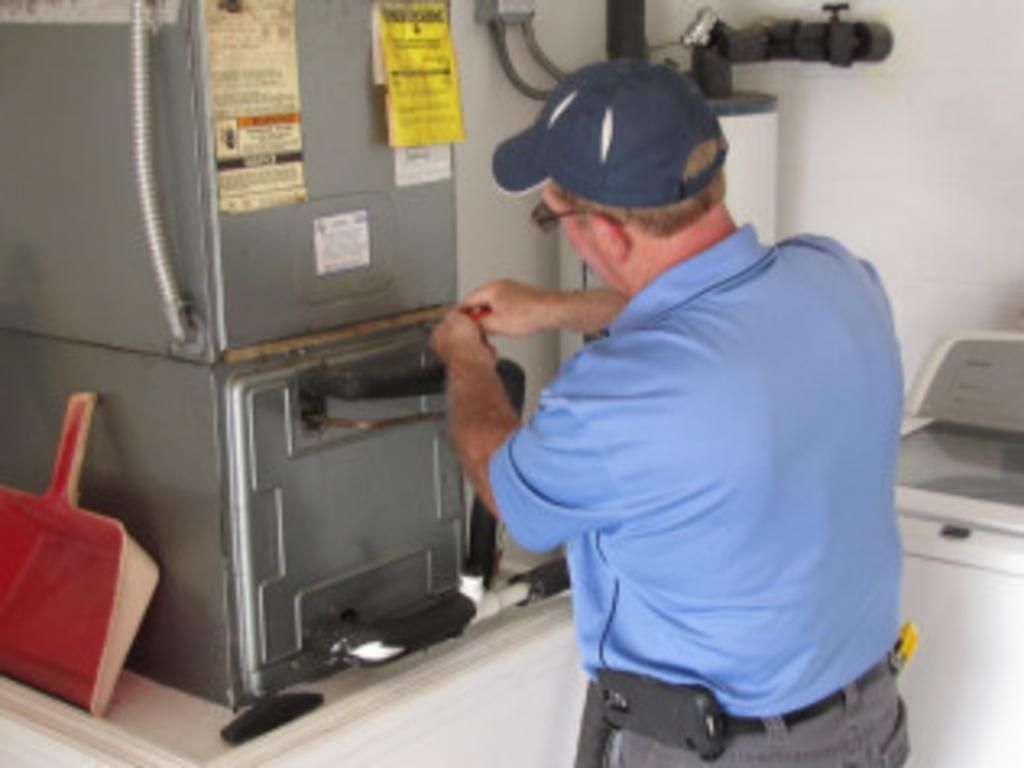 A man in a blue shirt is working on a refrigerator