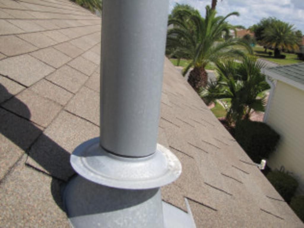 A chimney on top of a roof with palm trees in the background