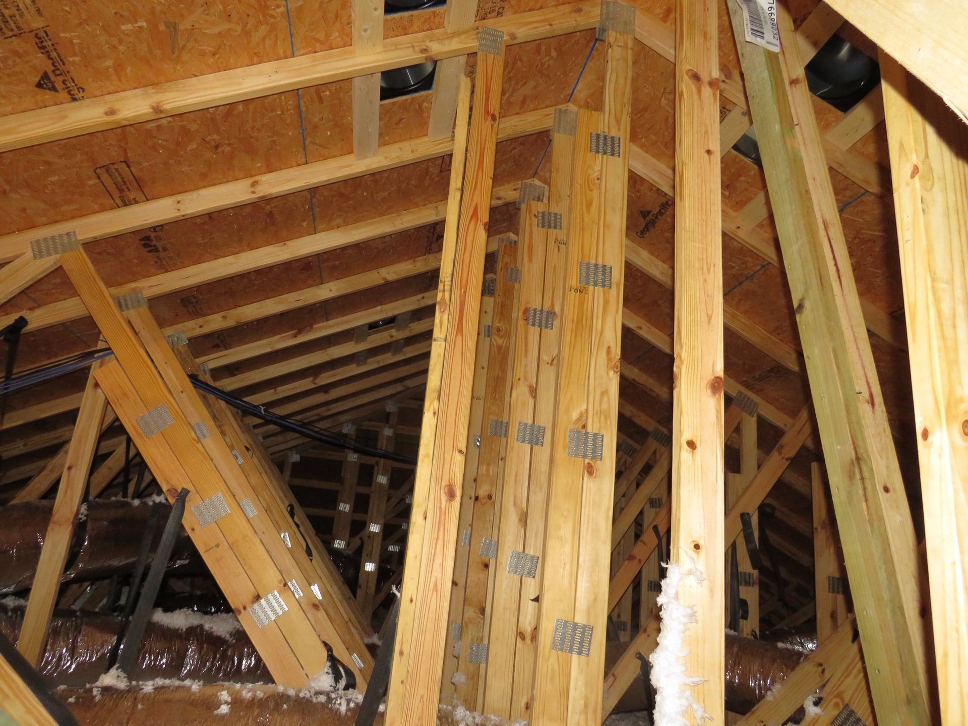 Wooden roof trusses and structural support beams inside an unfinished attic space.