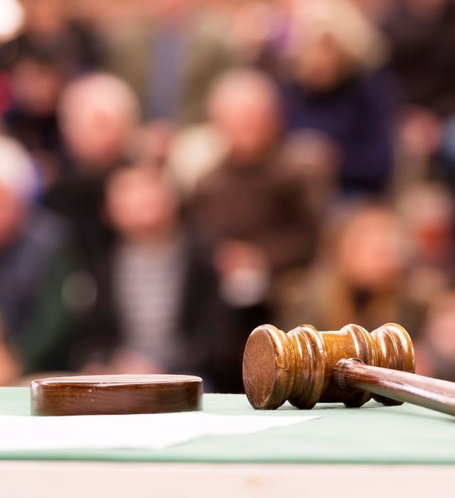 A wooden judge 's gavel is sitting on a table in front of a crowd.