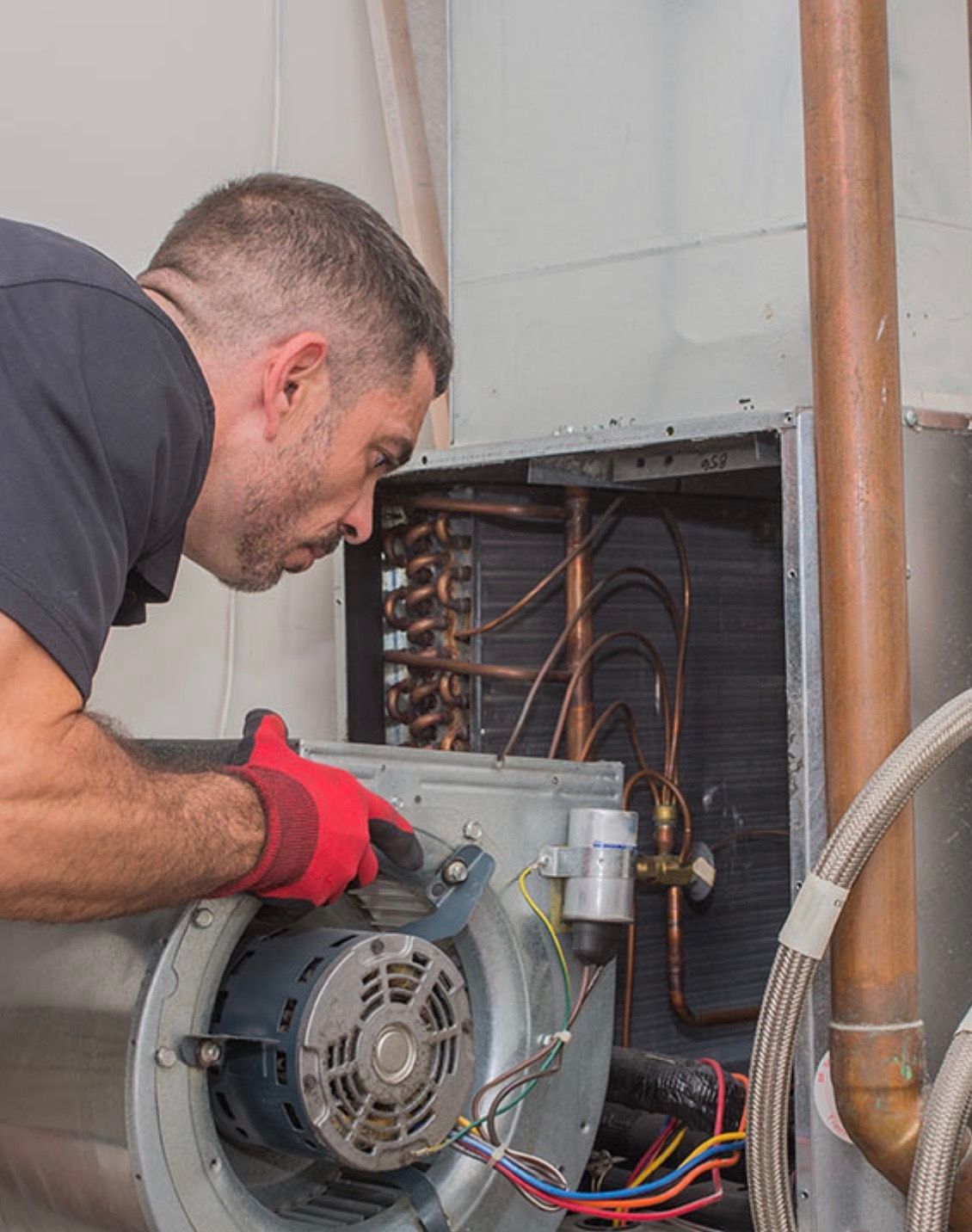 A man is working on a fan in a room.