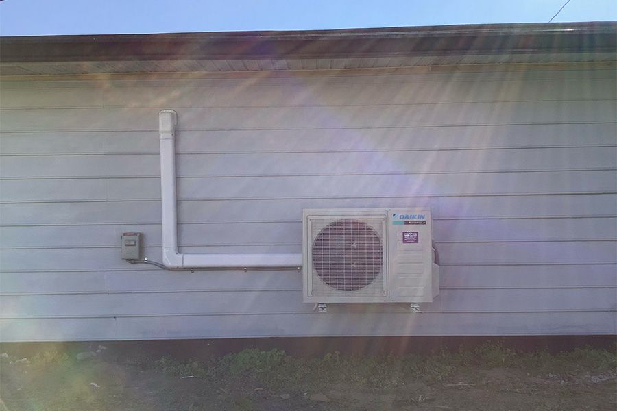 A white air conditioner is mounted on the side of a building.