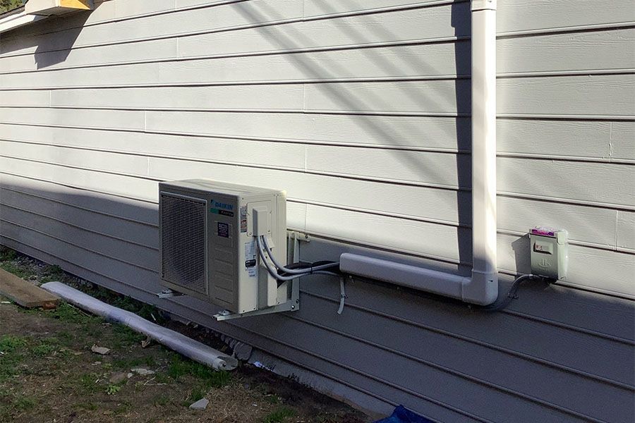 An air conditioner is installed on the side of a house.