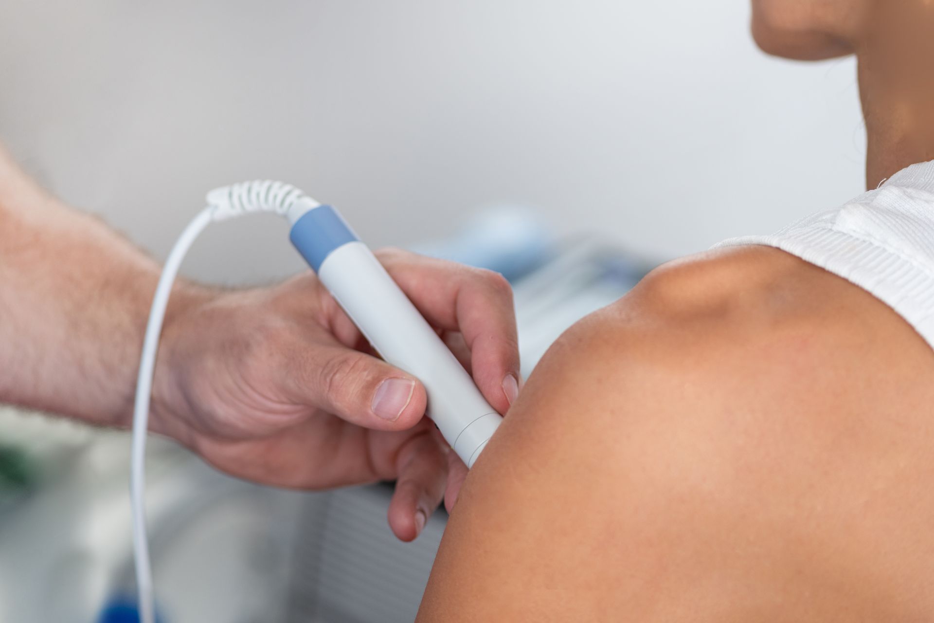 A healthcare provider uses a handheld ultrasound device on a patient's shoulder.