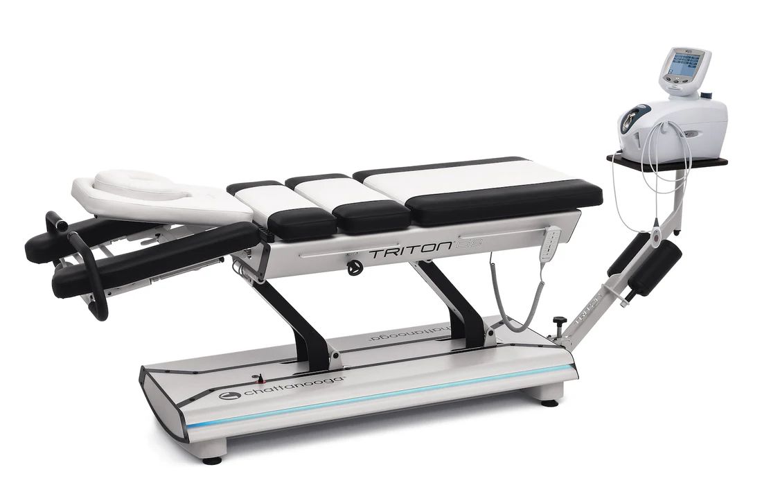 A black and white medical traction table with a computerized control unit on a mounted stand.