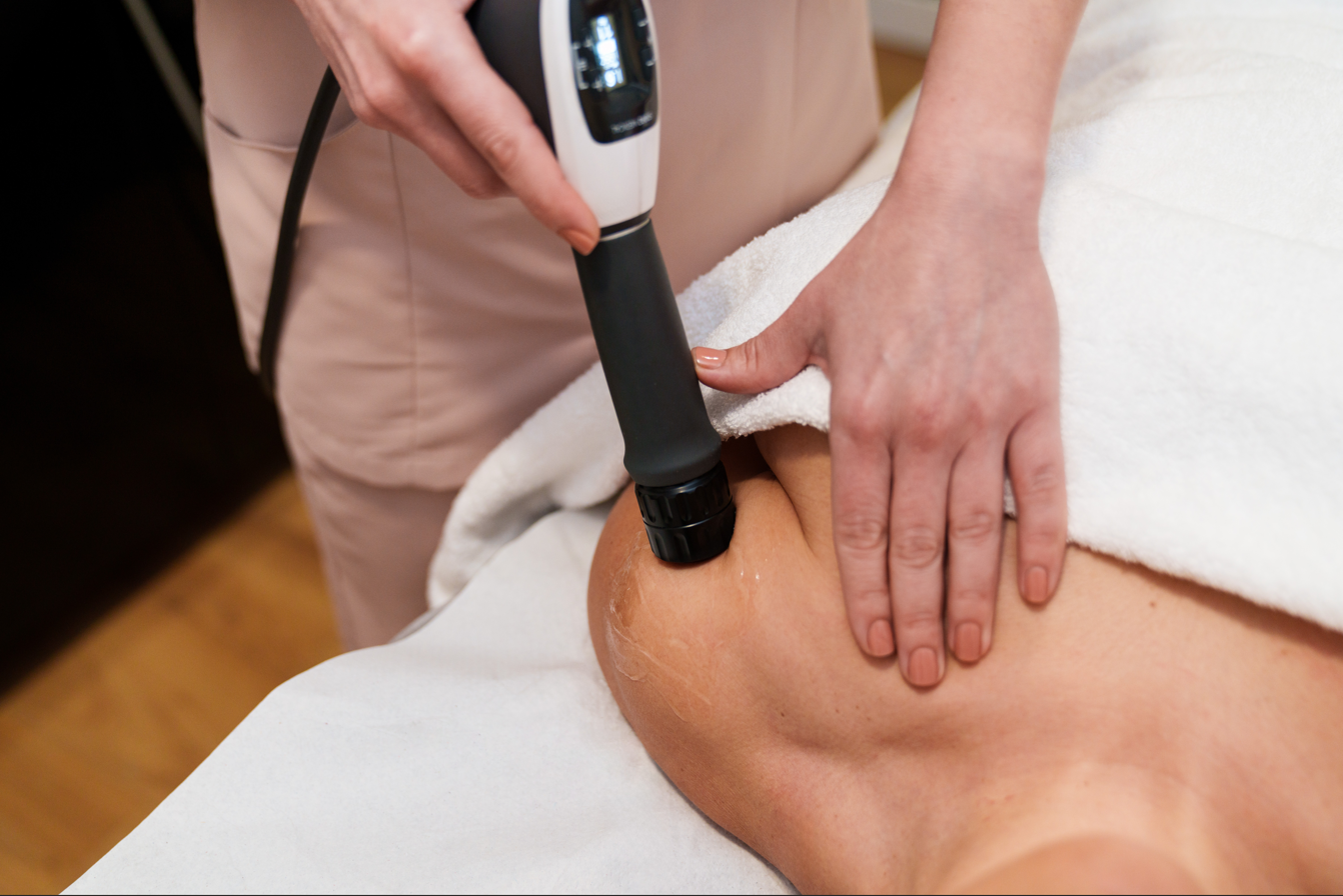 A woman is getting a massage on her shoulder with a machine.
