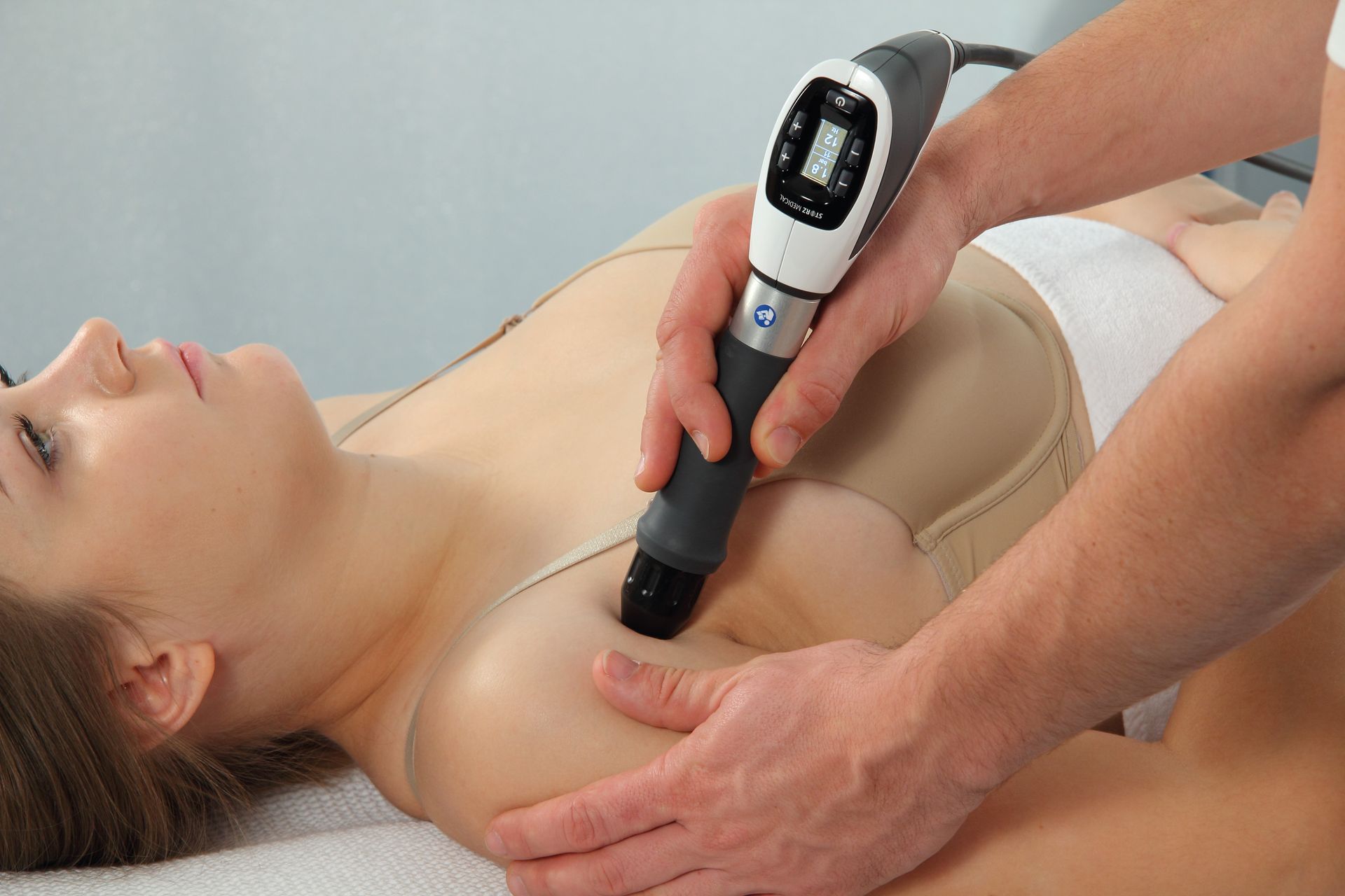 A woman is getting a massage with a machine on her chest.