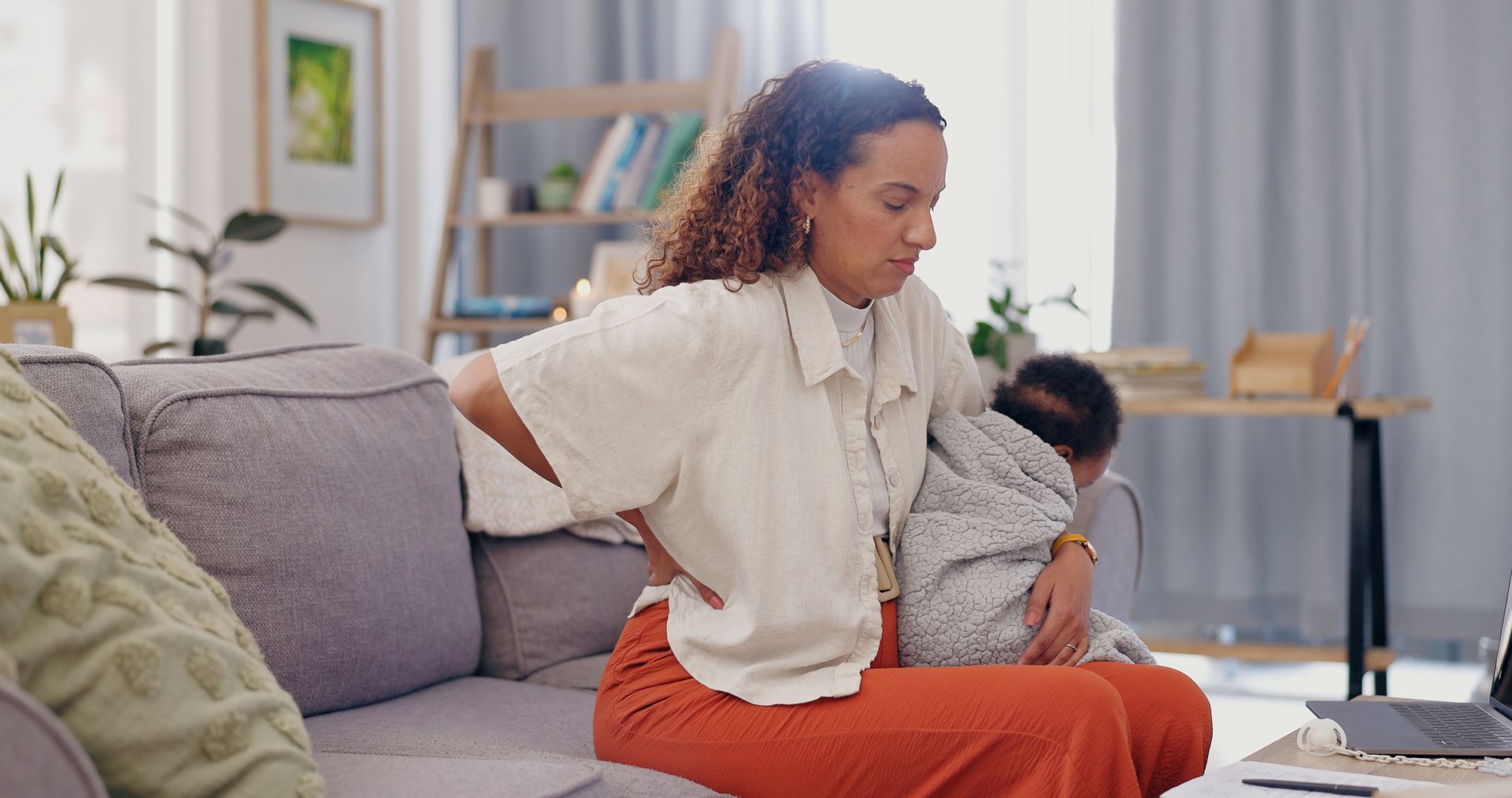 A woman is sitting on a couch holding a baby.
