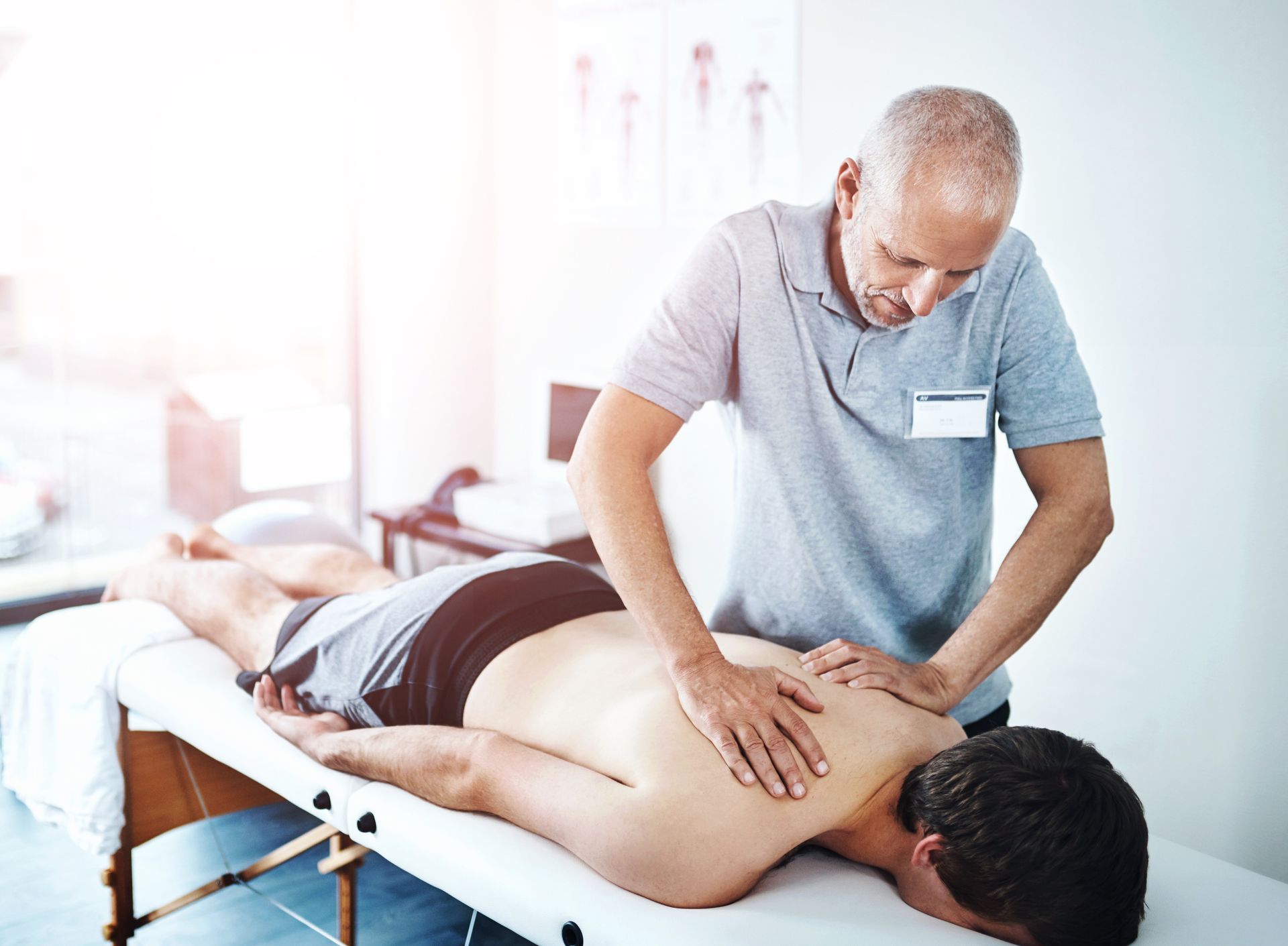 Physical therapist giving a back massage to a patient lying on a massage table.