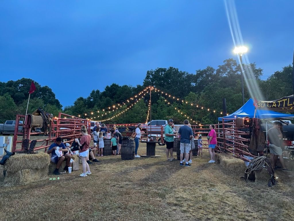A group of people are standing in a field at a rodeo.