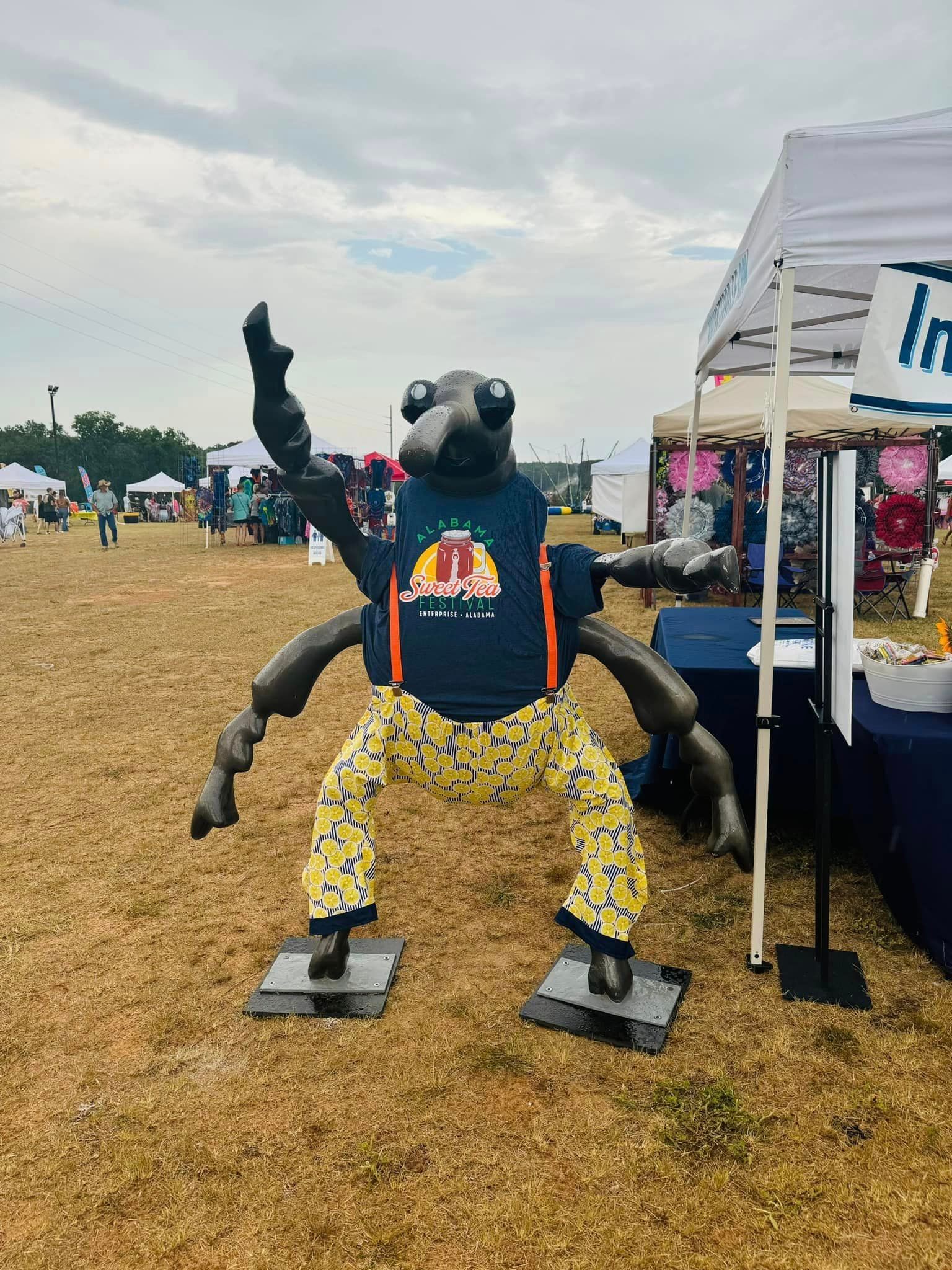 A statue of a spider wearing pajamas is standing in a field.