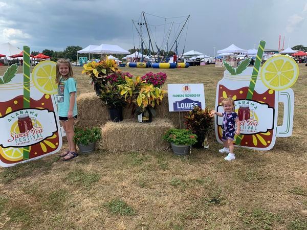 Two little girls are standing in front of a display of flowers.