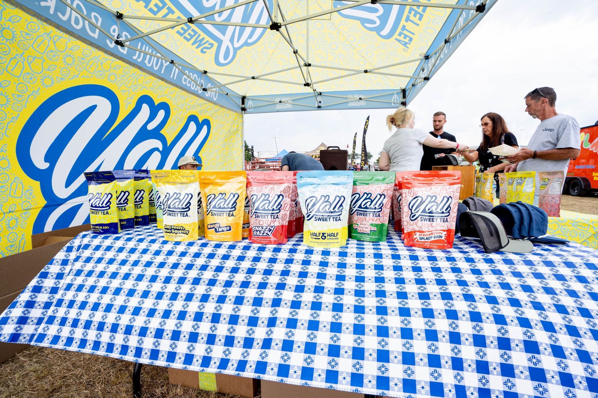 A table with a blue and white checkered table cloth under a tent.