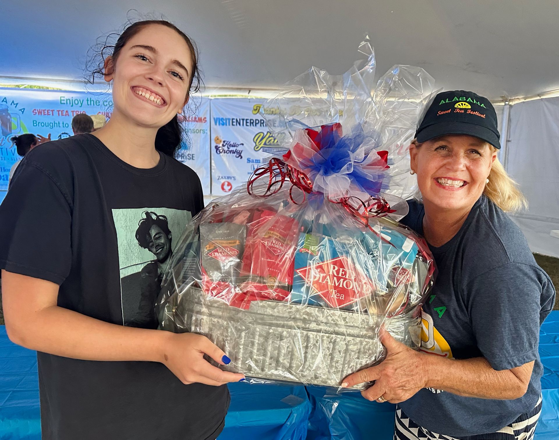Two women are standing next to each other holding a basket.