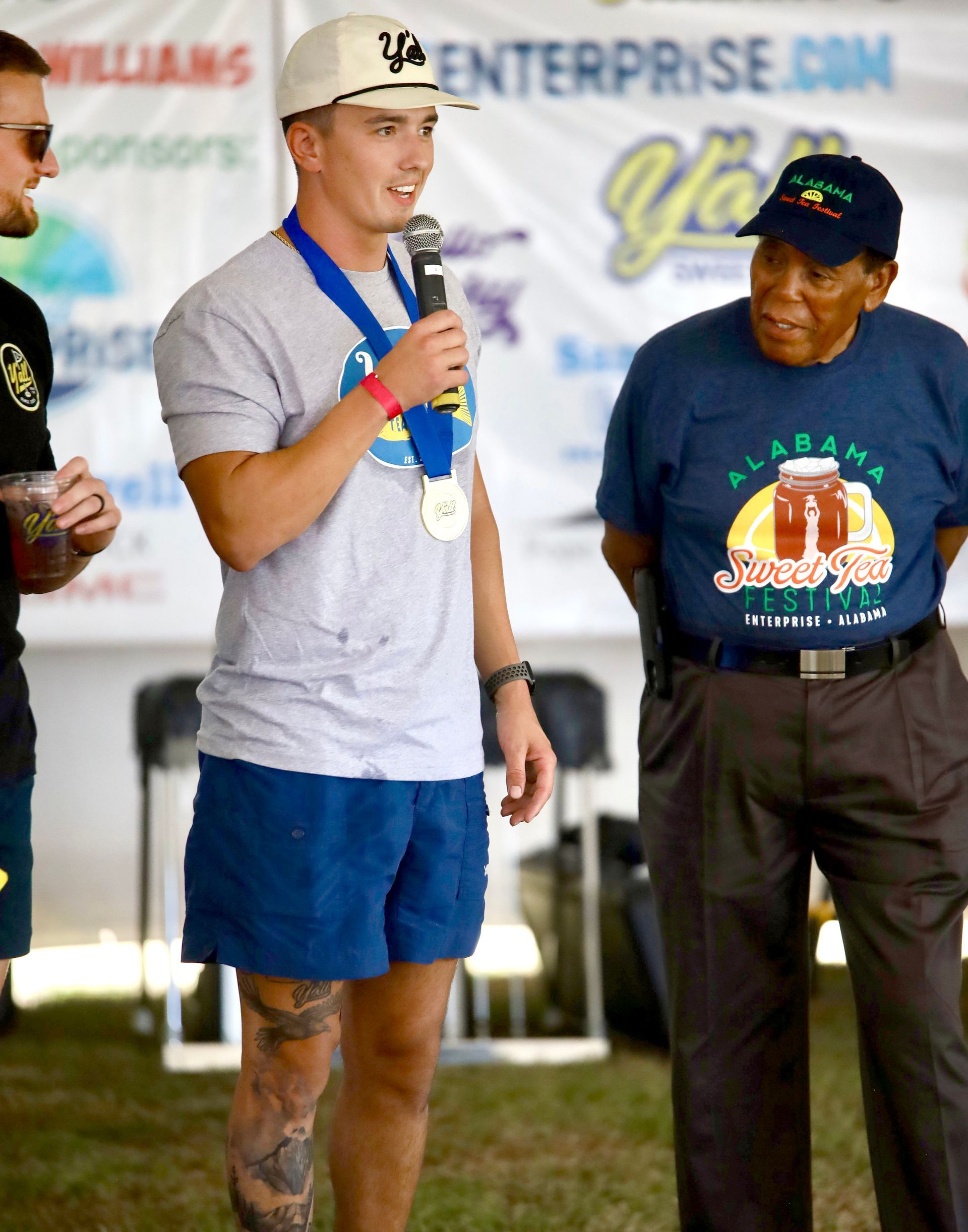 A man with a medal on his neck is speaking into a microphone
