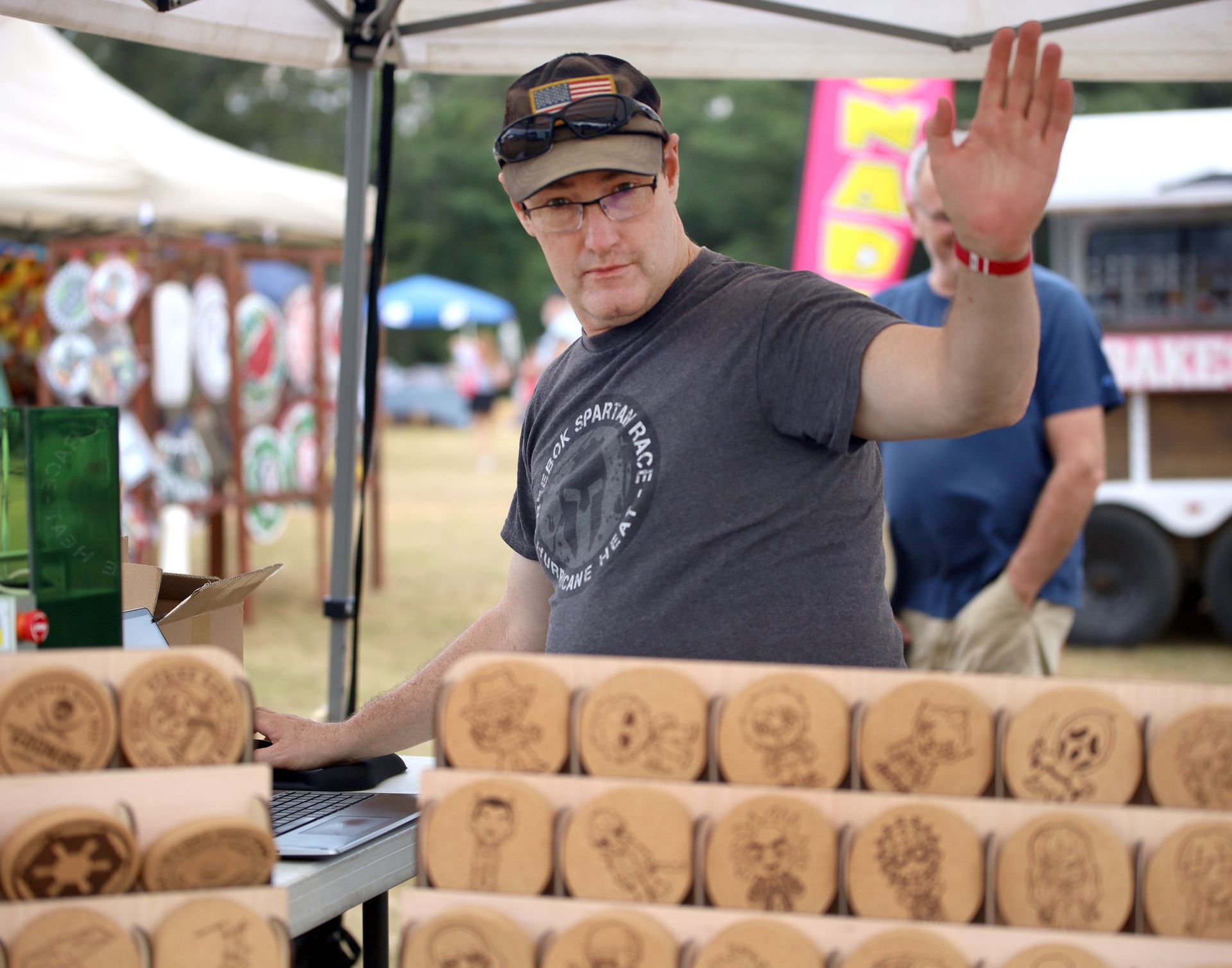 A man in a gray shirt is standing in front of a table with a bunch of cookies on it.