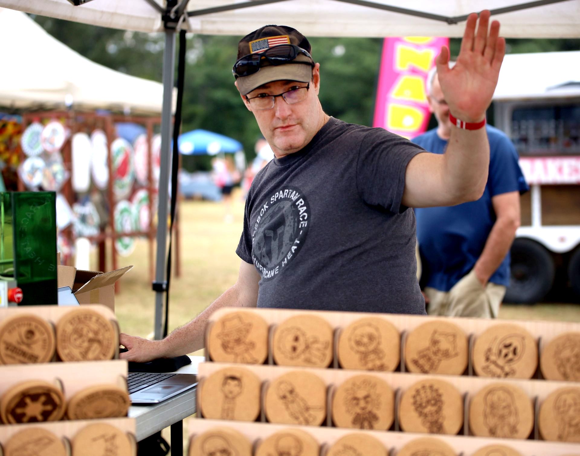 A man in a gray shirt is standing in front of a table with a bunch of cookies on it.