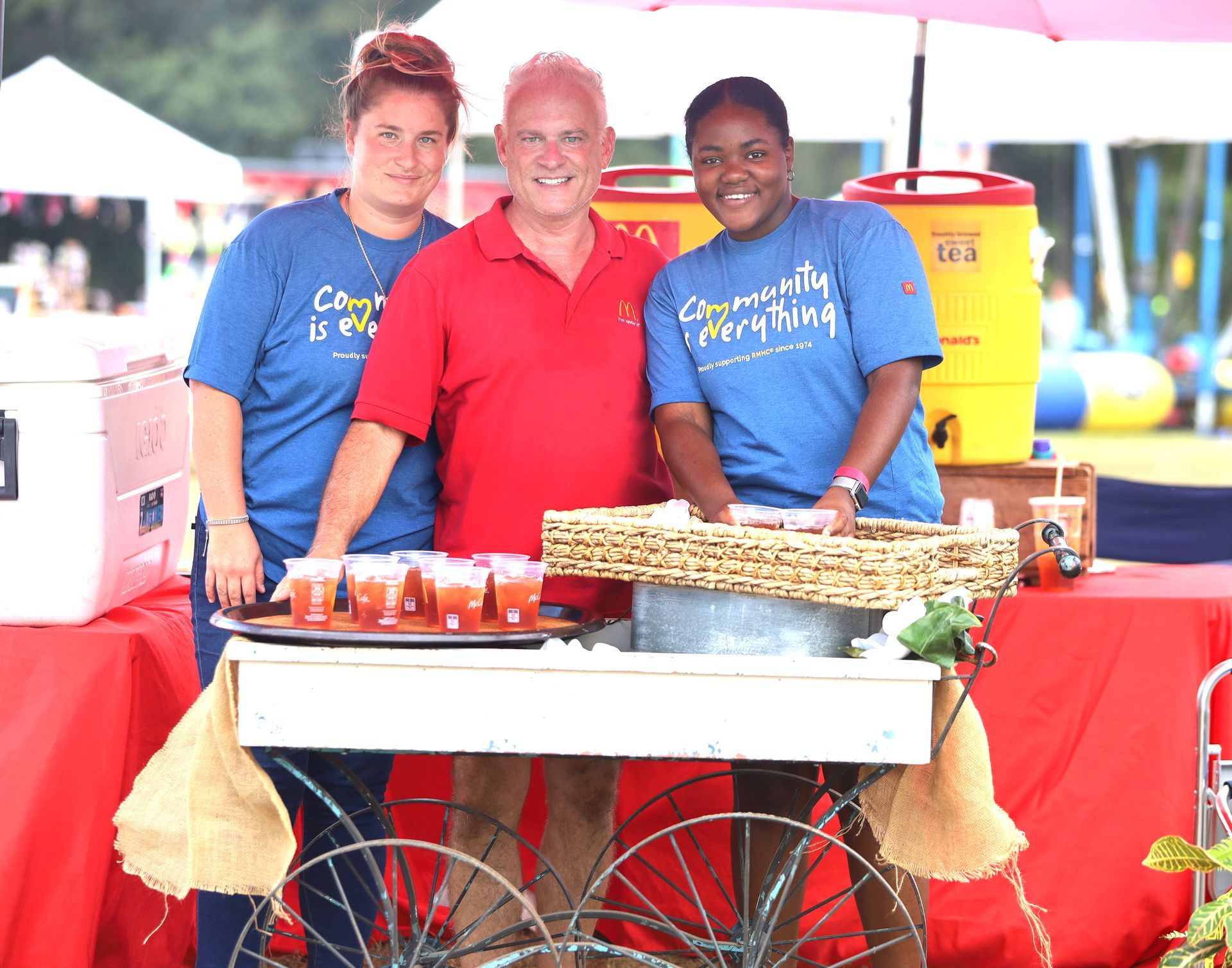 A man and two women are standing in front of a cart that says community everything