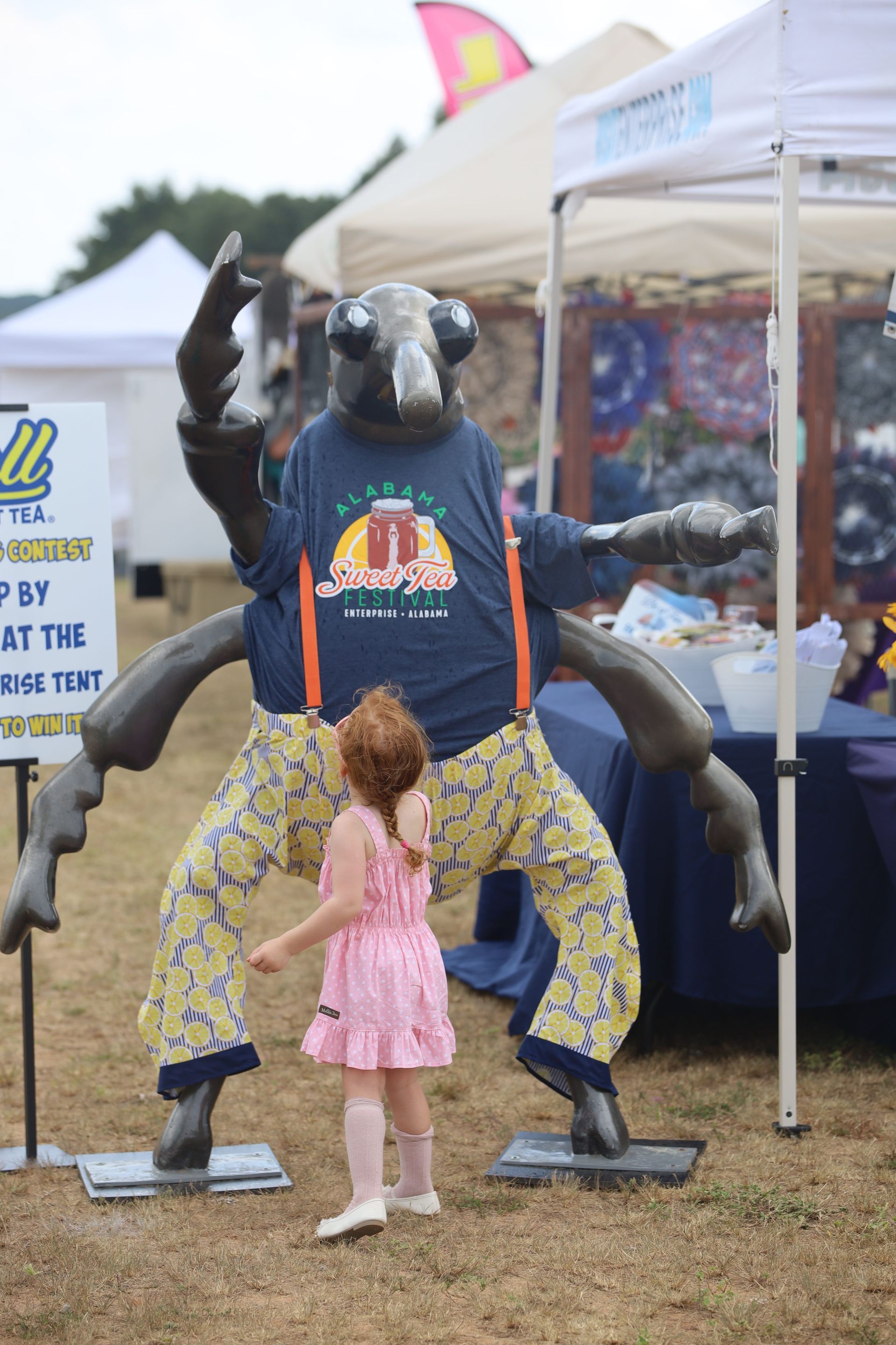 A little girl is standing next to a statue of a bug.