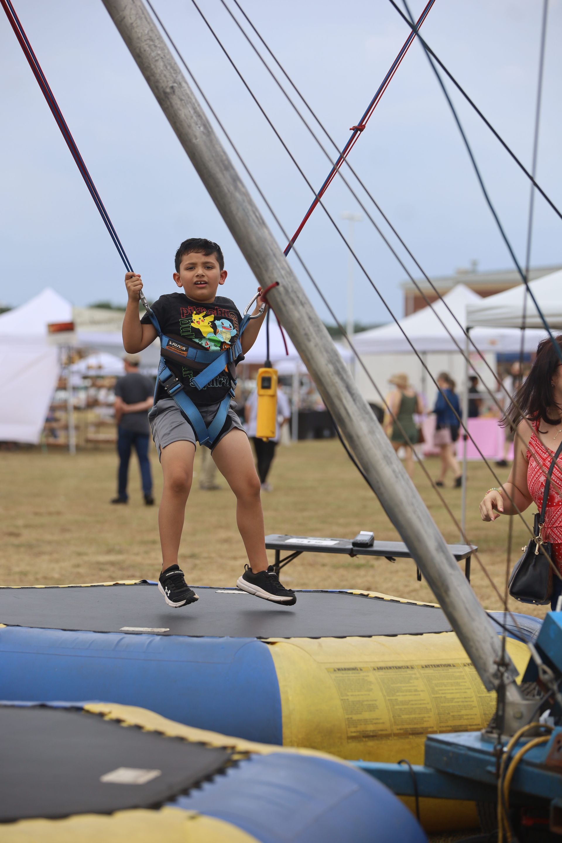 A young boy is riding a trampoline at a carnival.