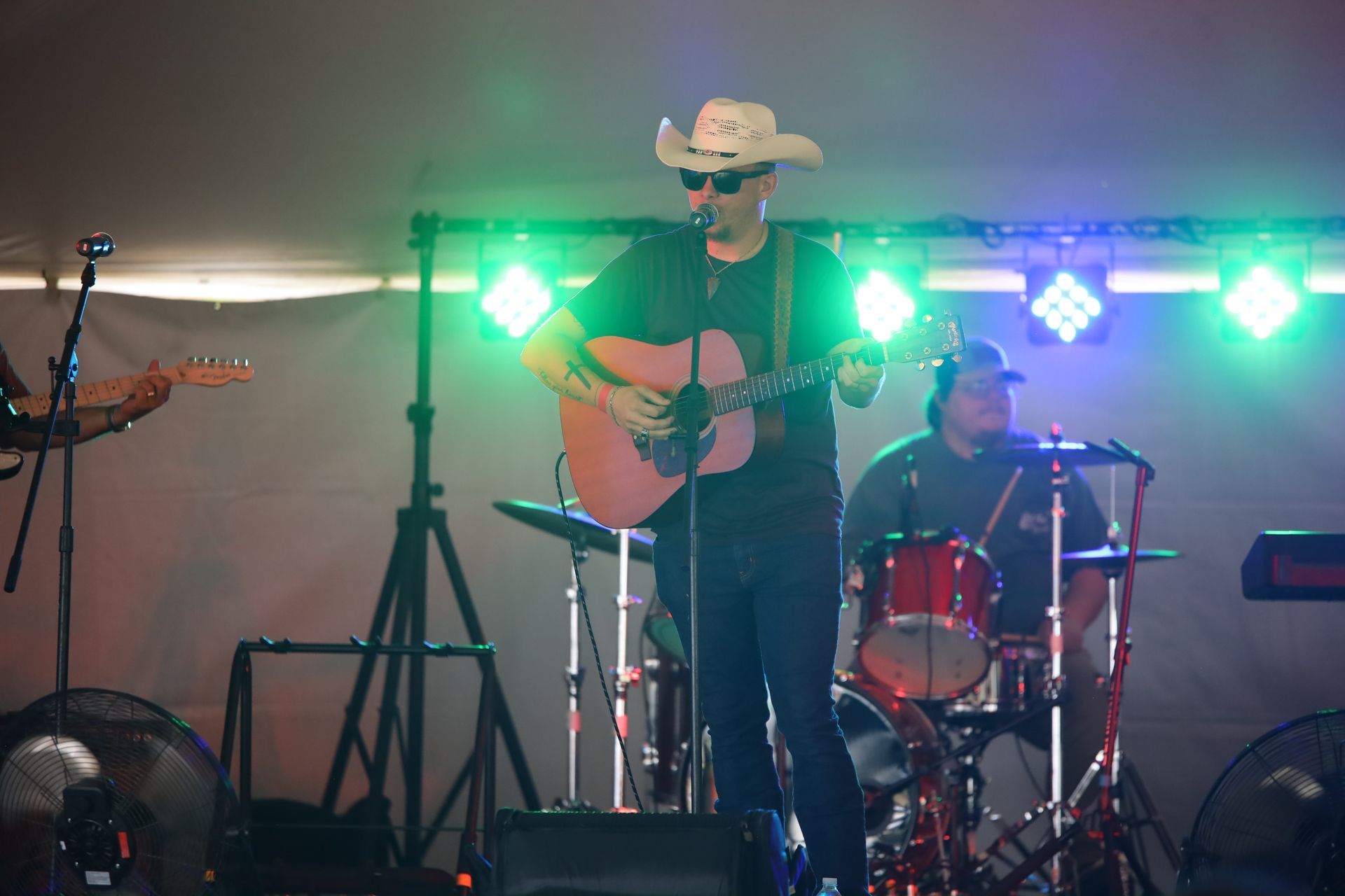A man in a cowboy hat is playing a guitar on a stage.