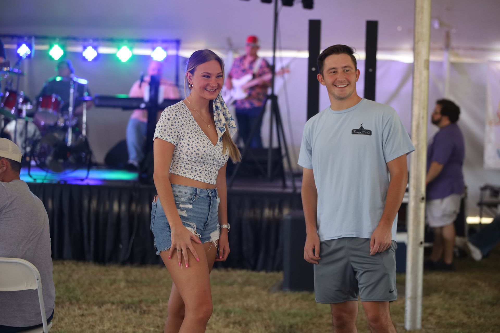 A man and a woman are standing next to each other in front of a stage.