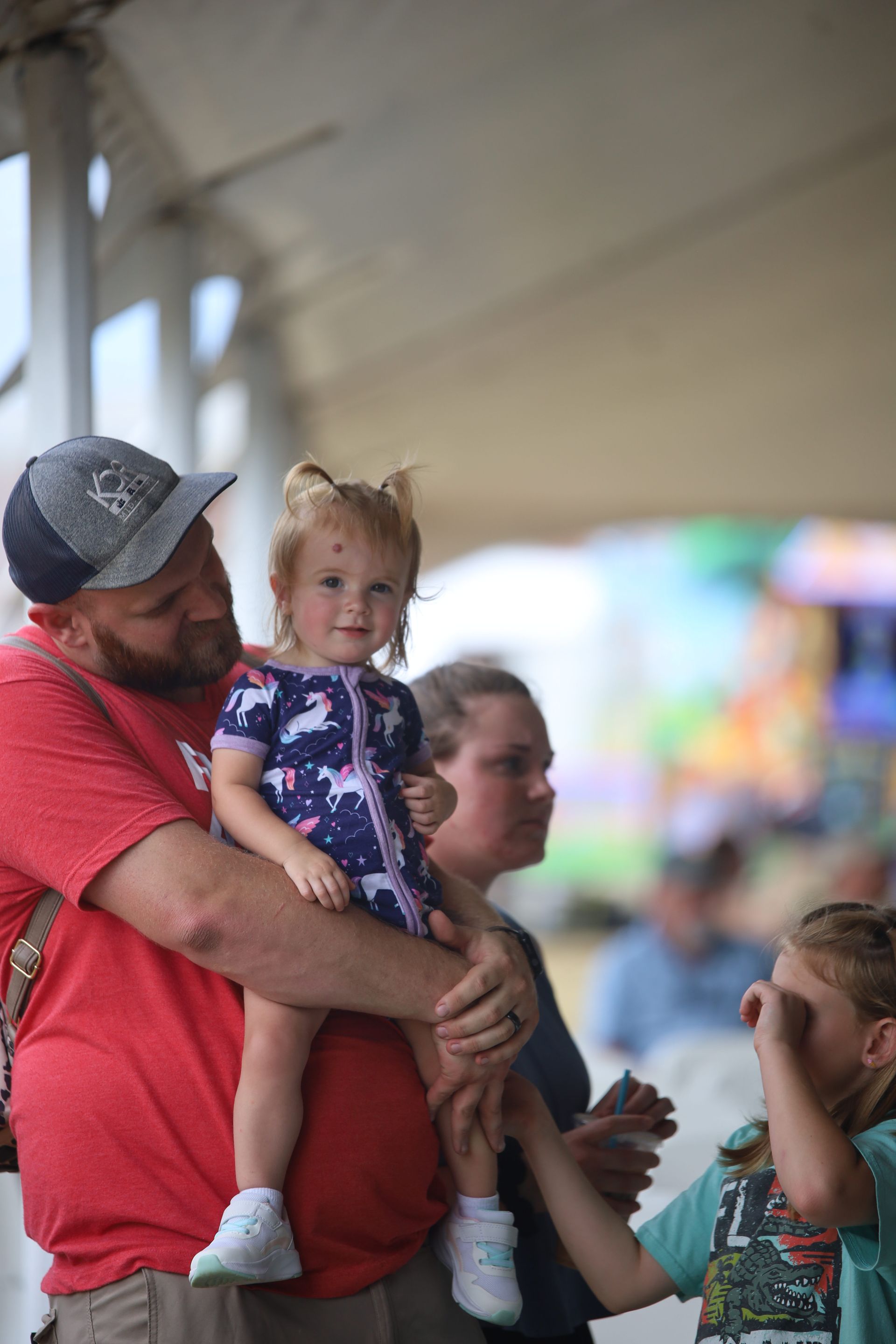 A man is holding a little girl in his arms at a carnival.