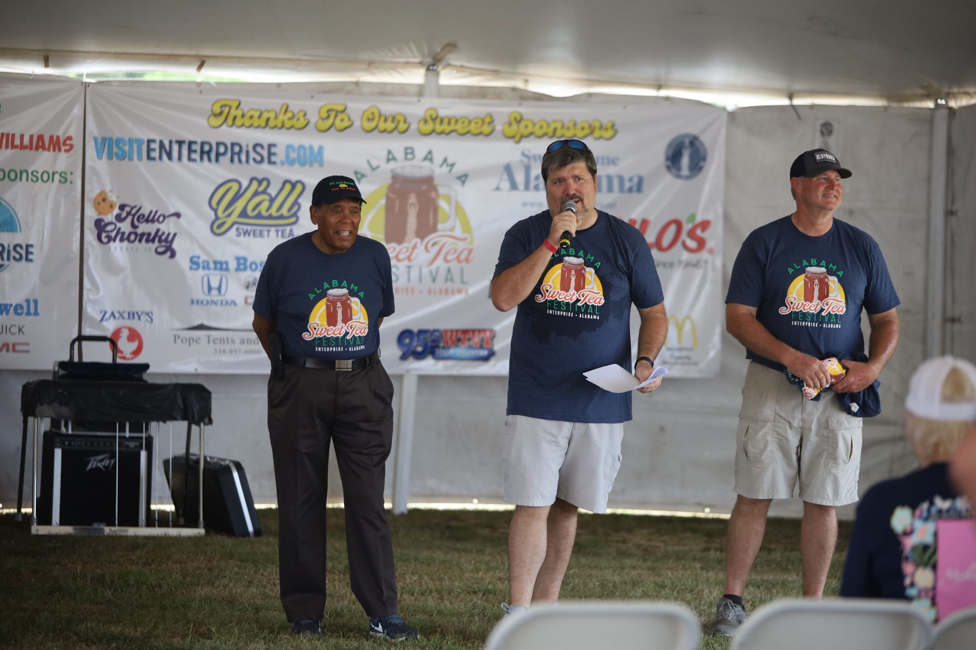 Three men are standing in front of a sign that says visitenterprise.com