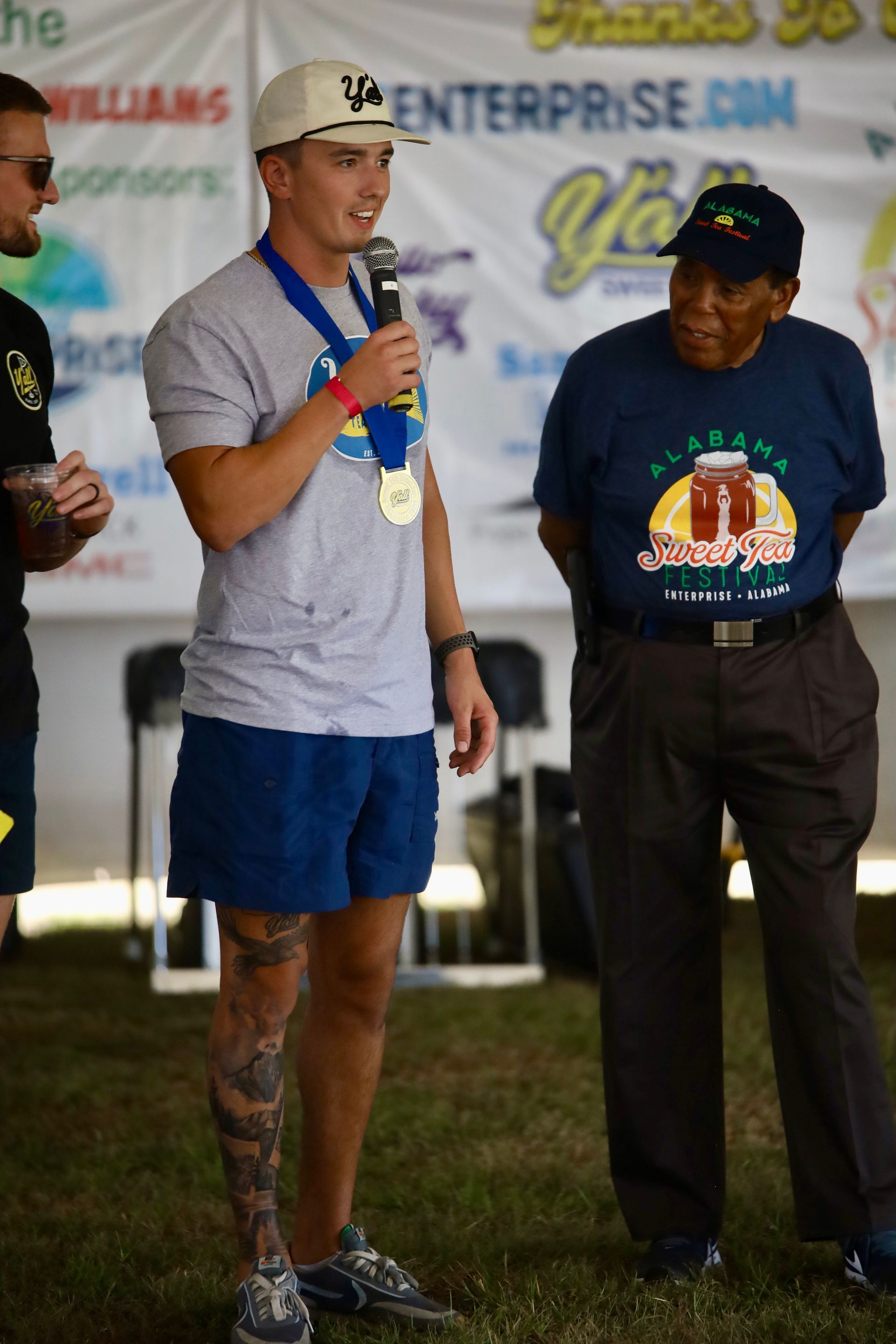 A man with a medal around his neck is speaking into a microphone