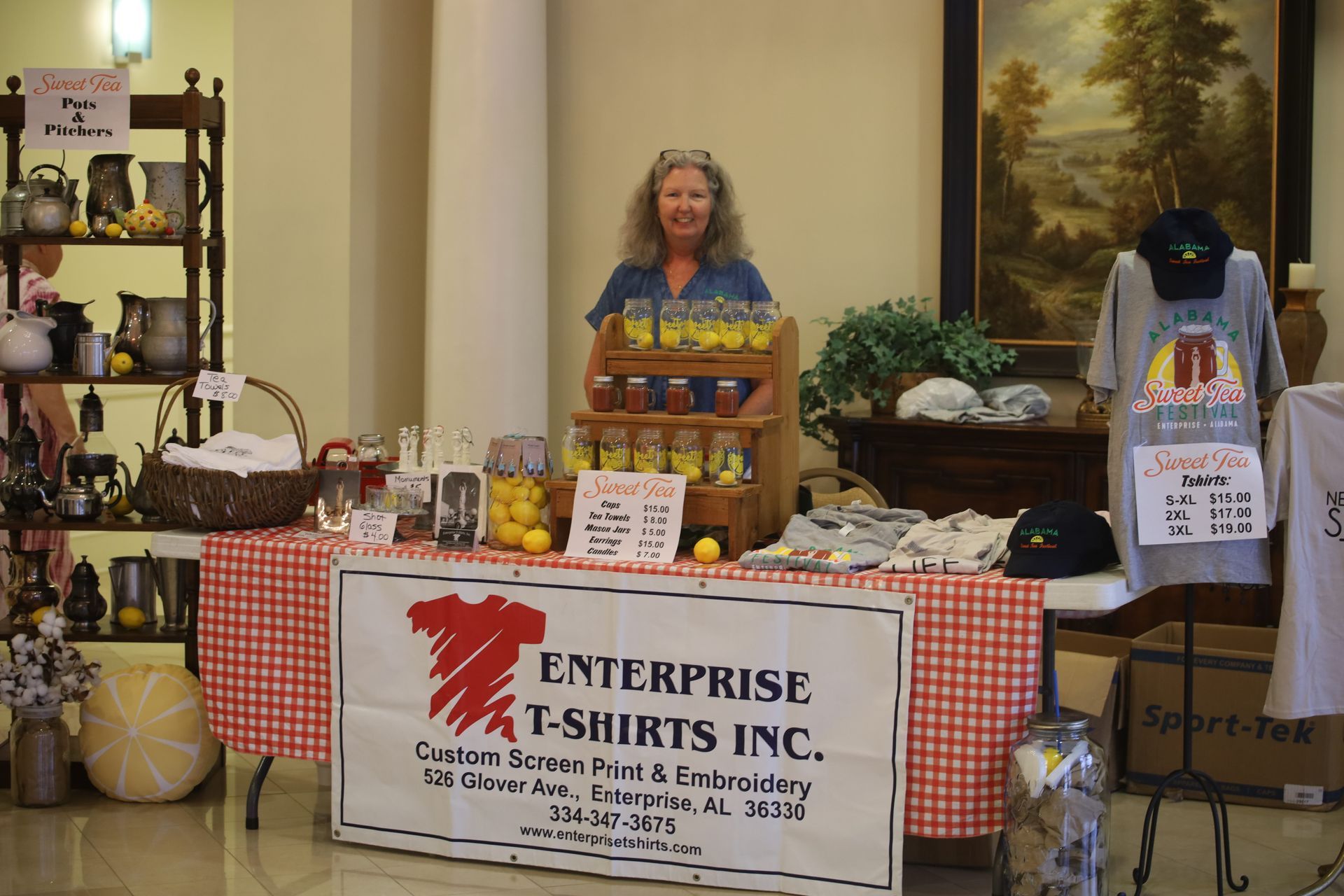 A woman is standing behind a table that says enterprise t-shirts inc.