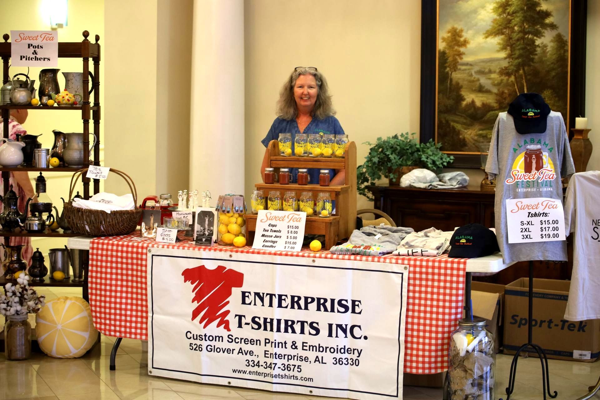 A woman is standing behind a table that says enterprise t-shirts inc.