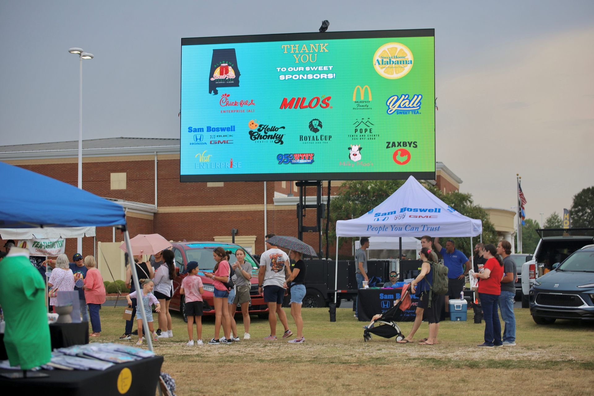 A group of people are standing in front of a large screen.