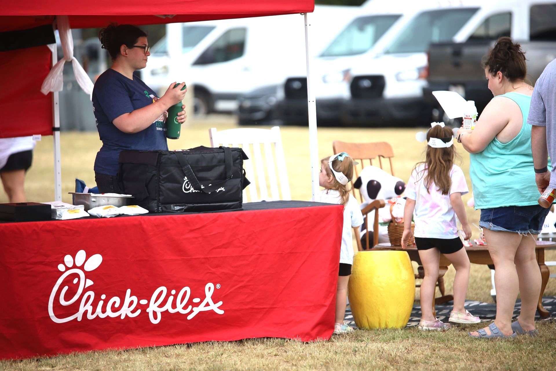 A group of people are standing around a chick-fil-a table.