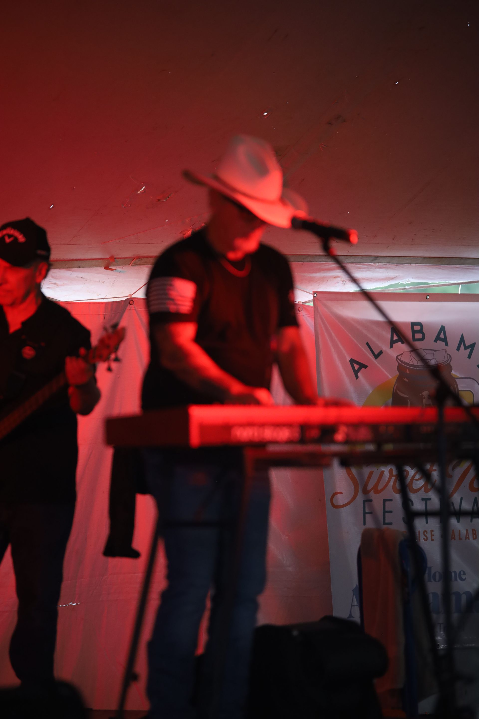 A man in a cowboy hat is playing a keyboard on stage
