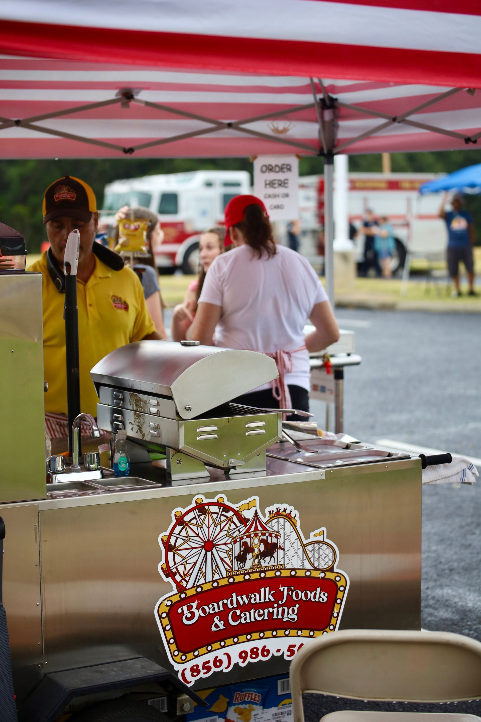 A man in a yellow shirt is standing in front of a food stand