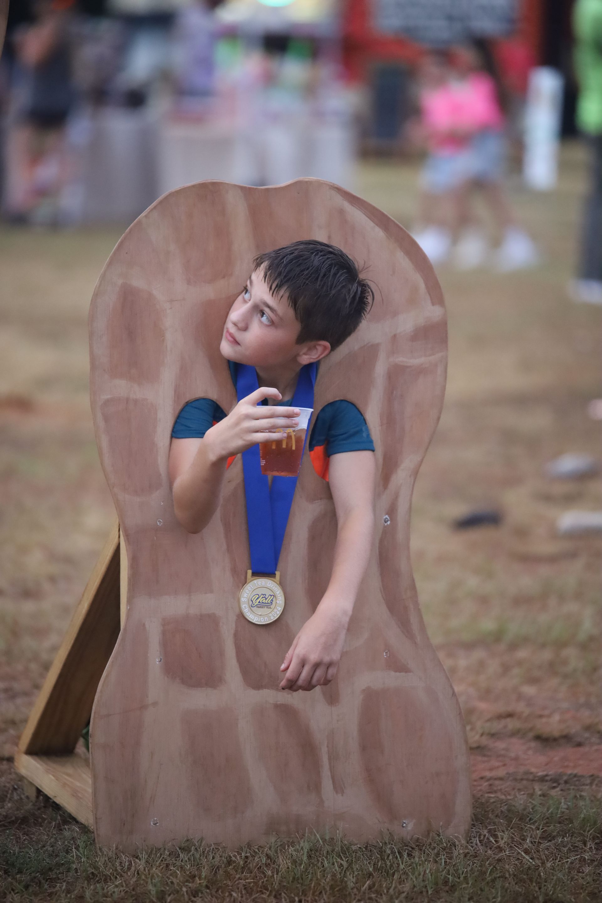 A young boy is sitting in a cardboard peanut with a medal around his neck.