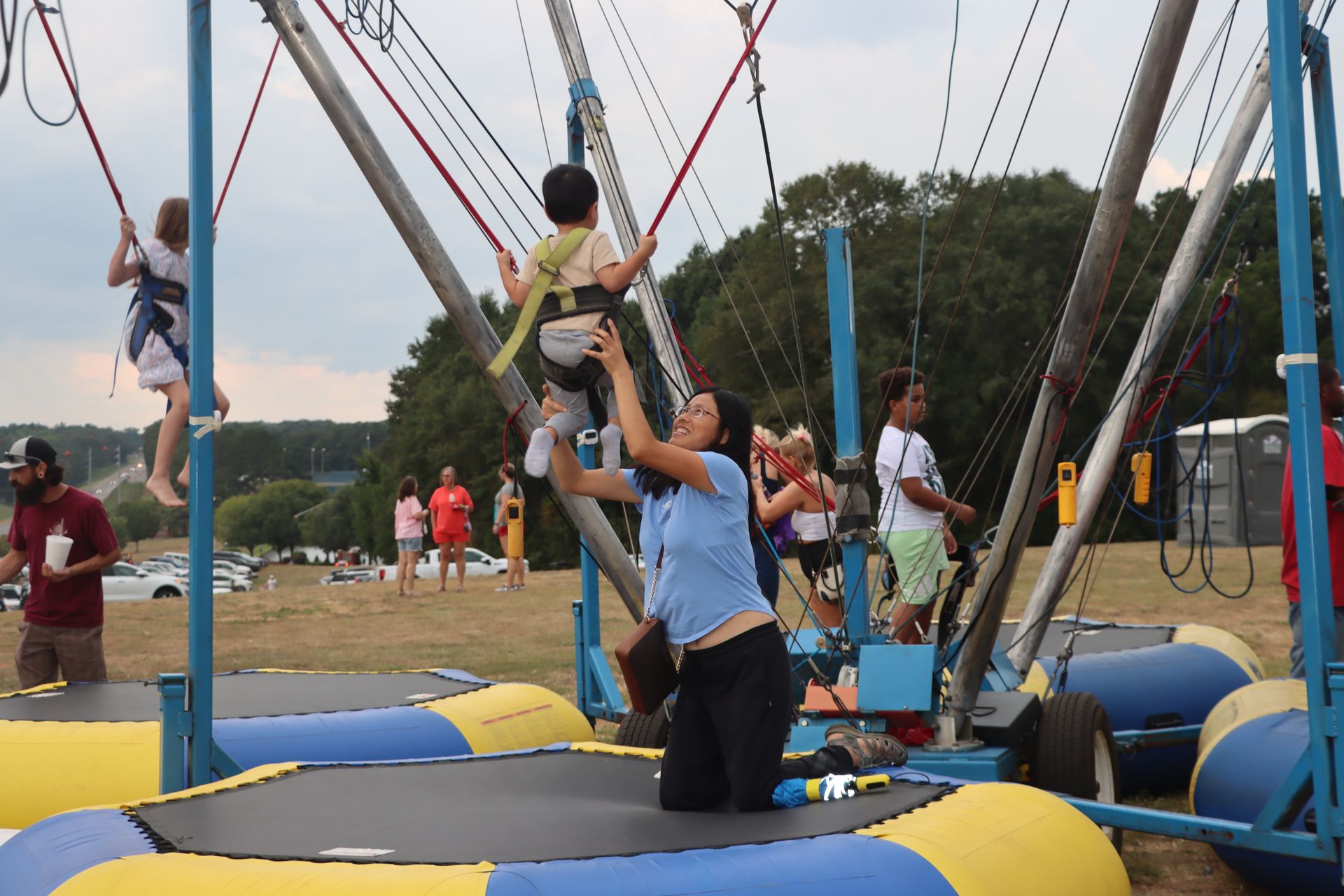 A woman is kneeling on a trampoline holding a child