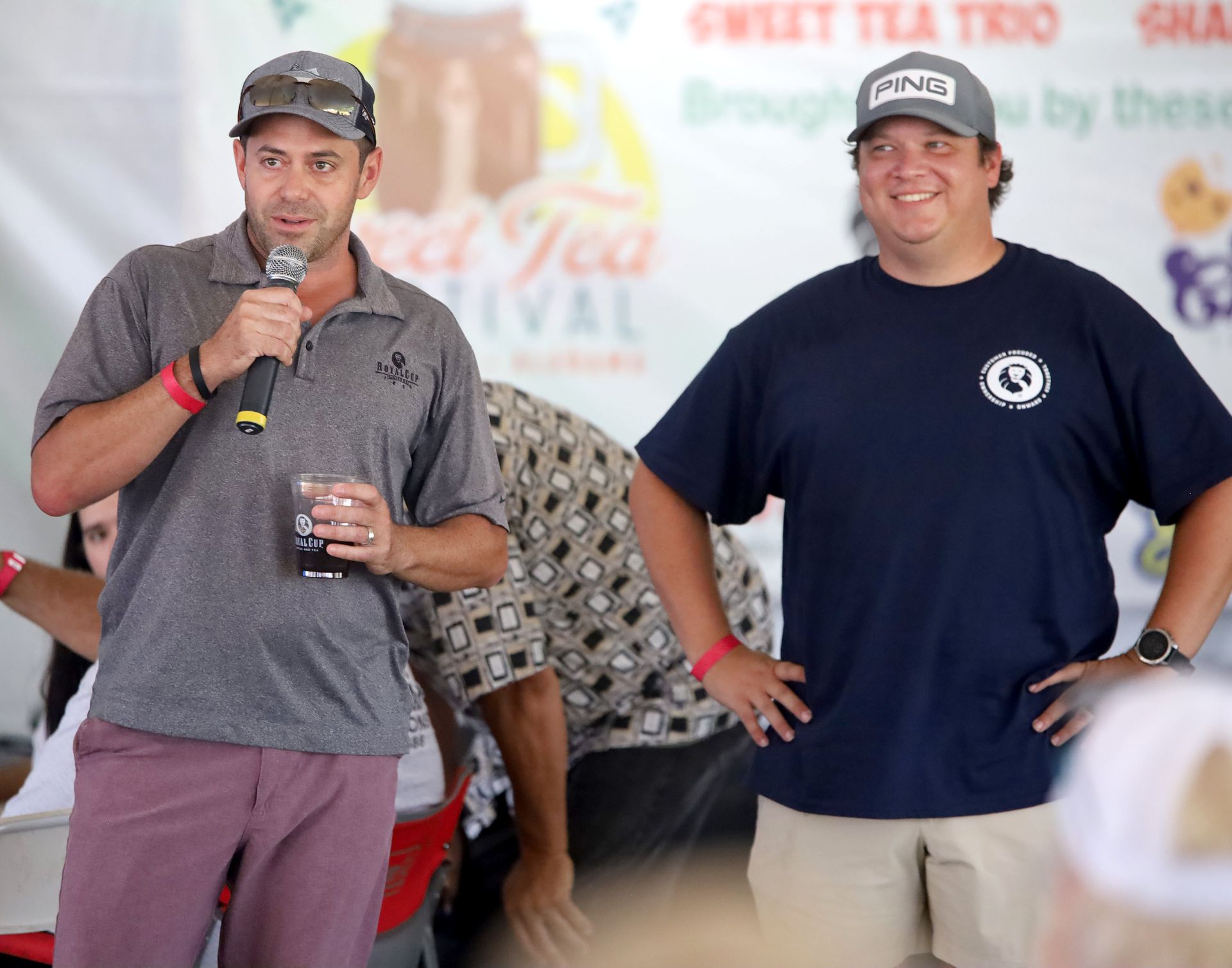 Two men are standing in front of a sign that says sweet tea festival