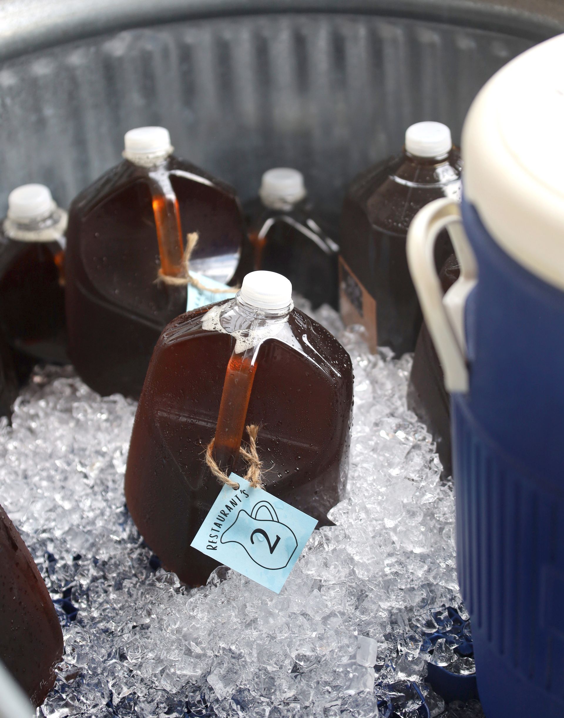 Bottles of iced tea in a bucket with a tag that says 2