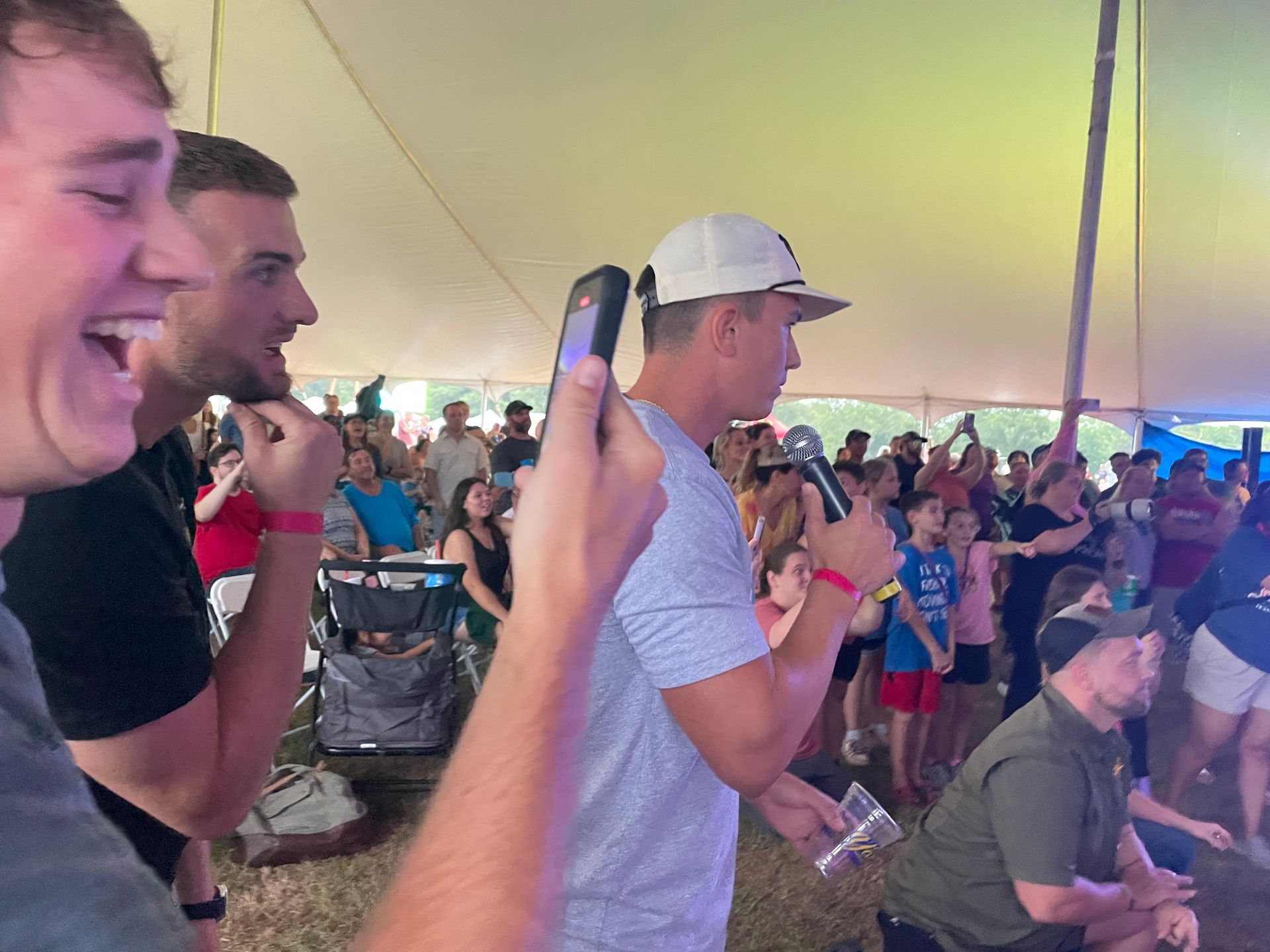 A man is holding a cell phone in front of a crowd of people.