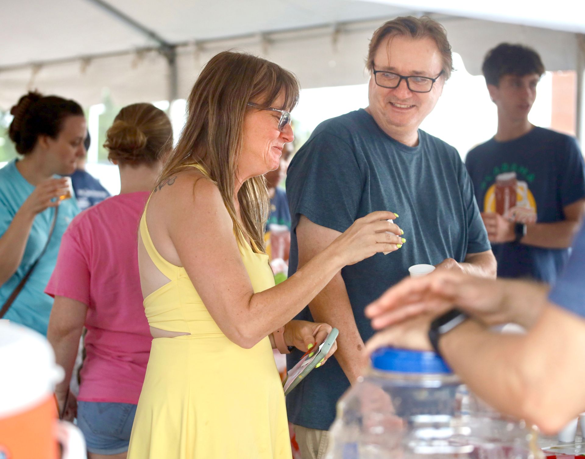 A woman in a yellow dress is talking to a man in a blue shirt