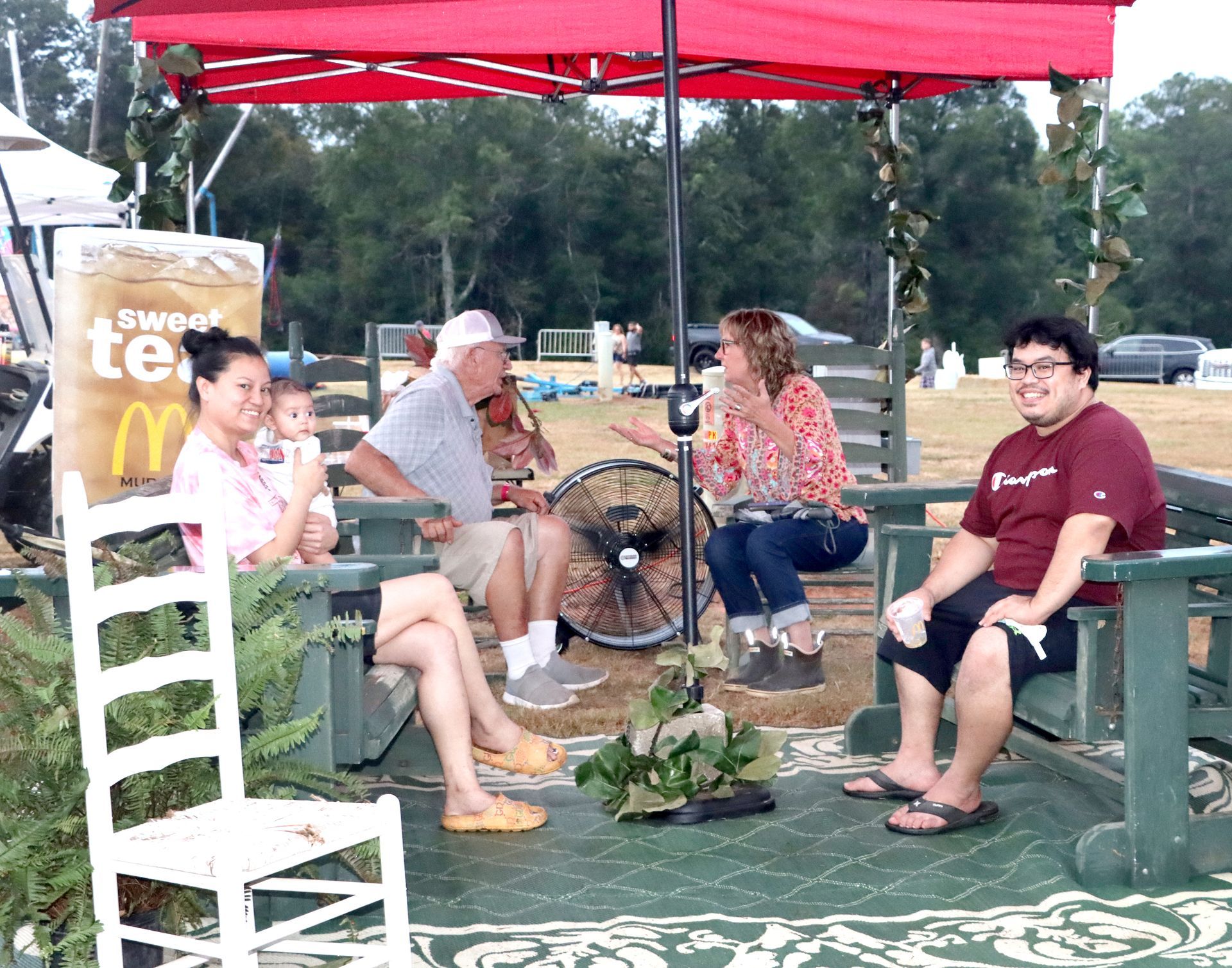 A group of people are sitting under an umbrella in front of a mcdonald 's sign