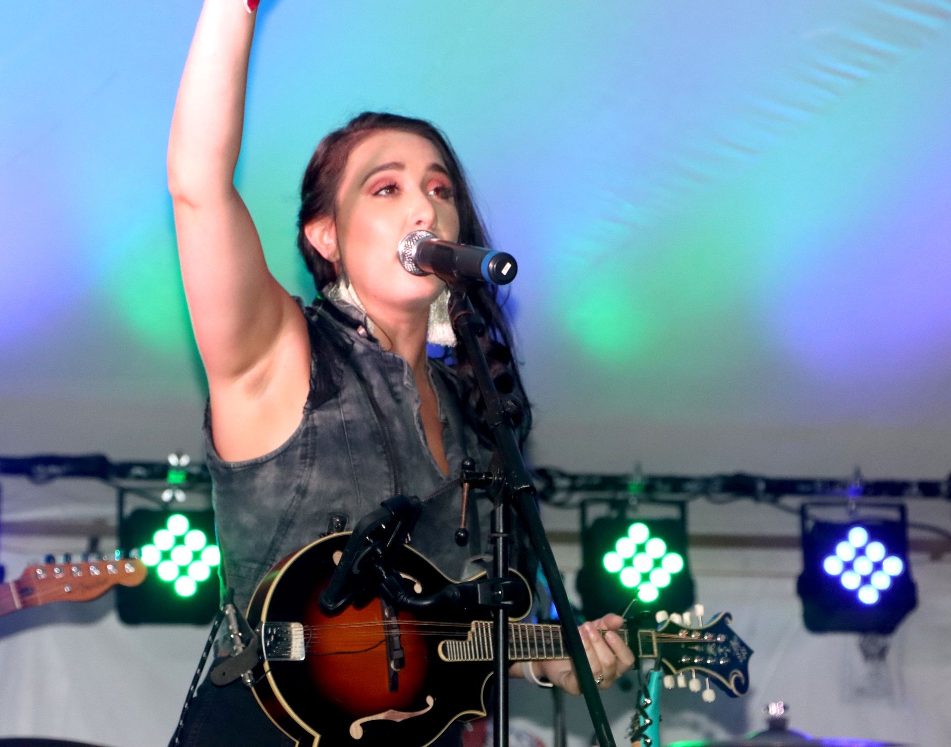 A woman singing into a microphone while playing a guitar