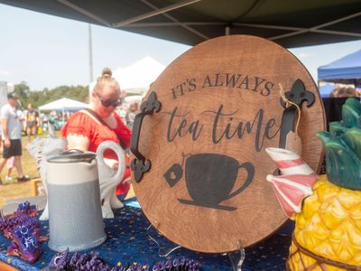 A sign that says `` it 's always tea time '' is sitting on a table. Alabama Sweet Tea Festival
