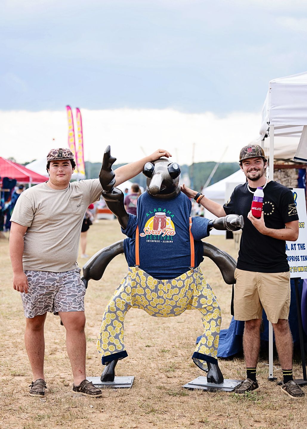 Two men are standing next to a statue of a bug.