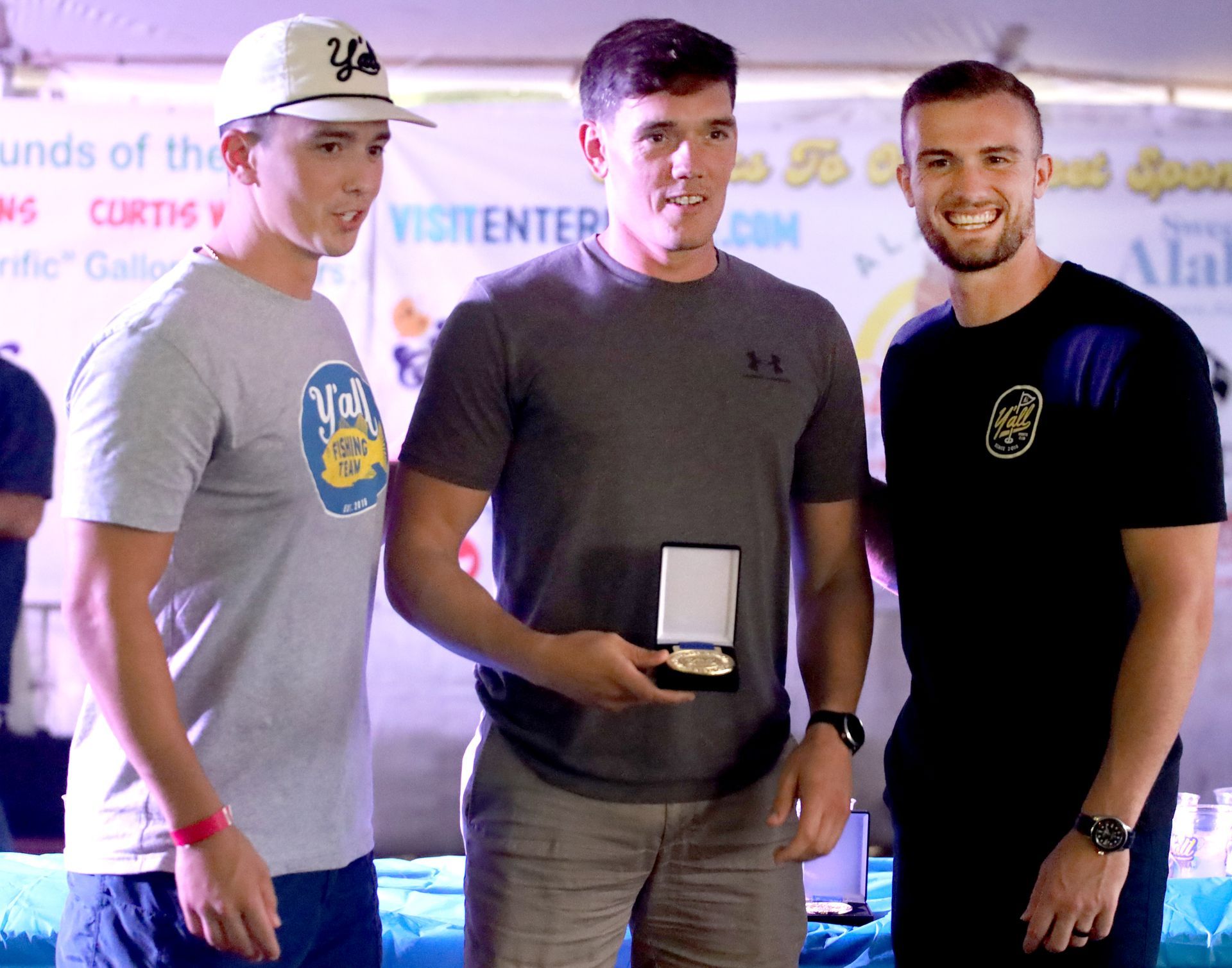 Three men are posing for a picture with one wearing a ya hat
