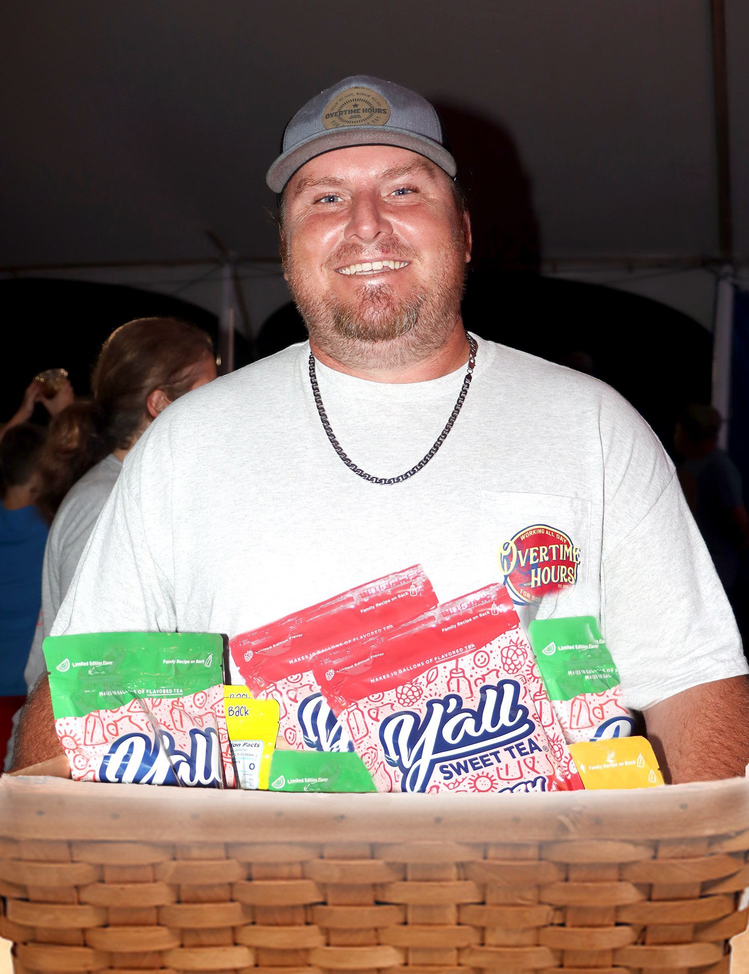 A man in a white shirt is holding a basket of popcorn