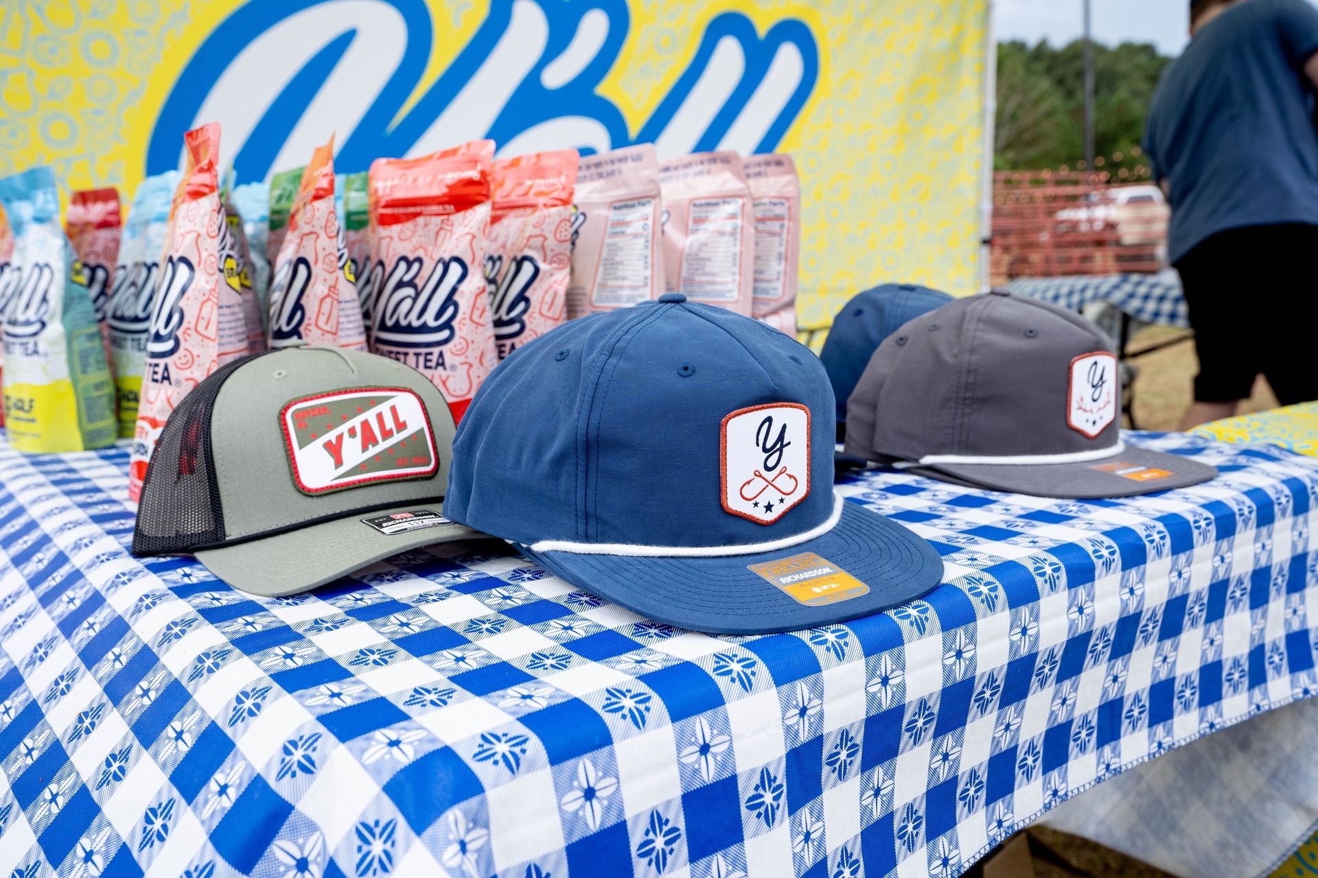 A table with a blue and white checkered table cloth and hats on it